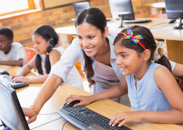 Cute pupils in computer class with teacher at the elementary school